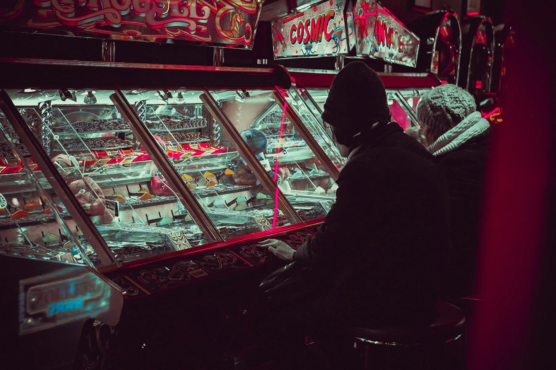 A person playing an arcade machine under colorful lights
